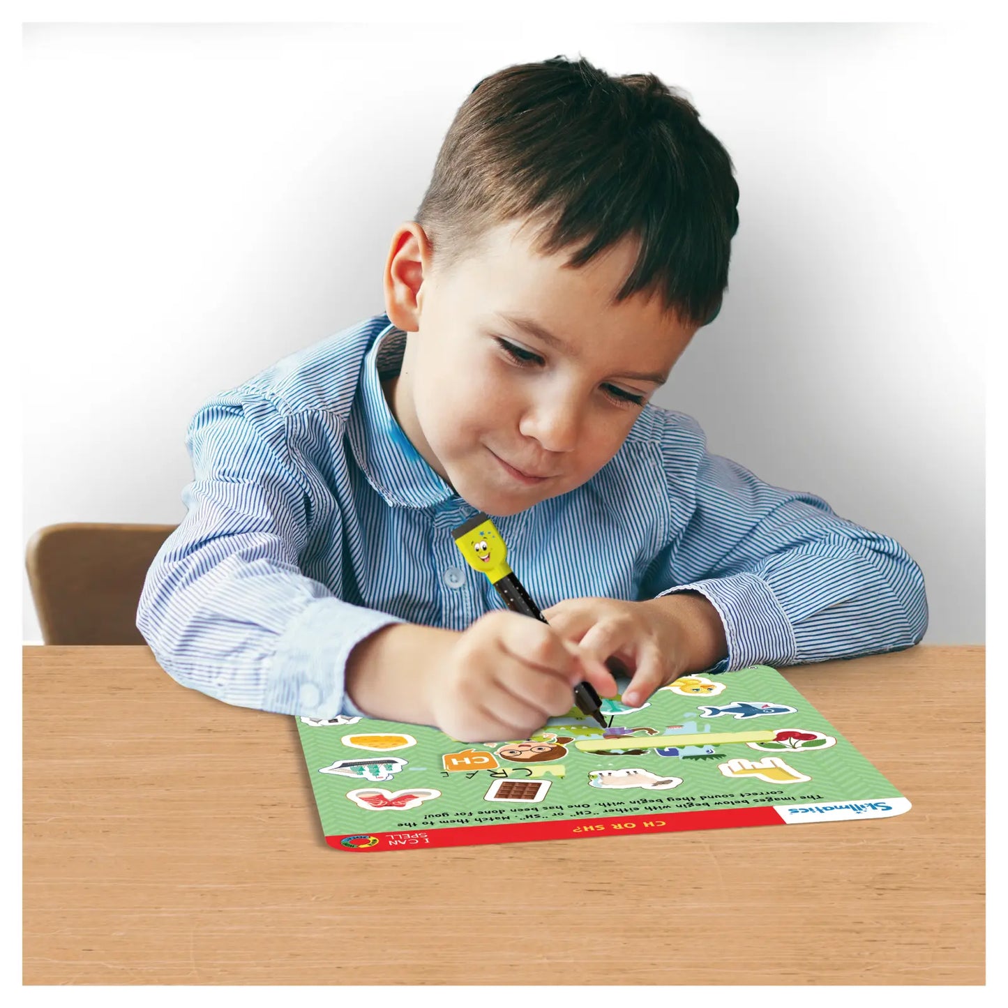 Child using a cartoon-topped pen on a Write and Wipe I Can Spell learning mat