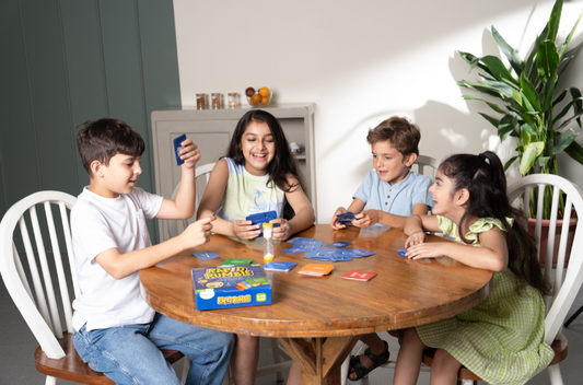 4 kids playing card game on table and laughing