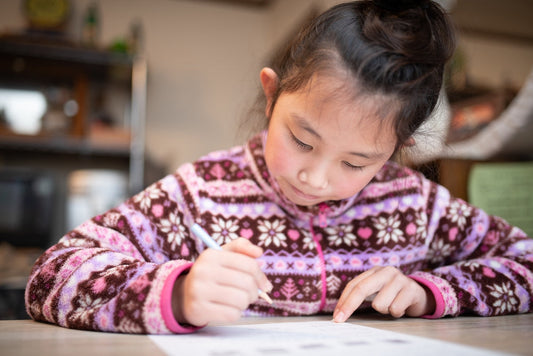 Little girl in sweater writing on a table