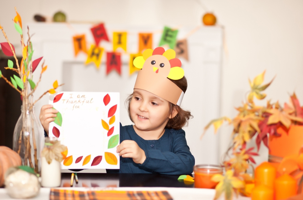 Kid holding a thanksgiving printable with the words 