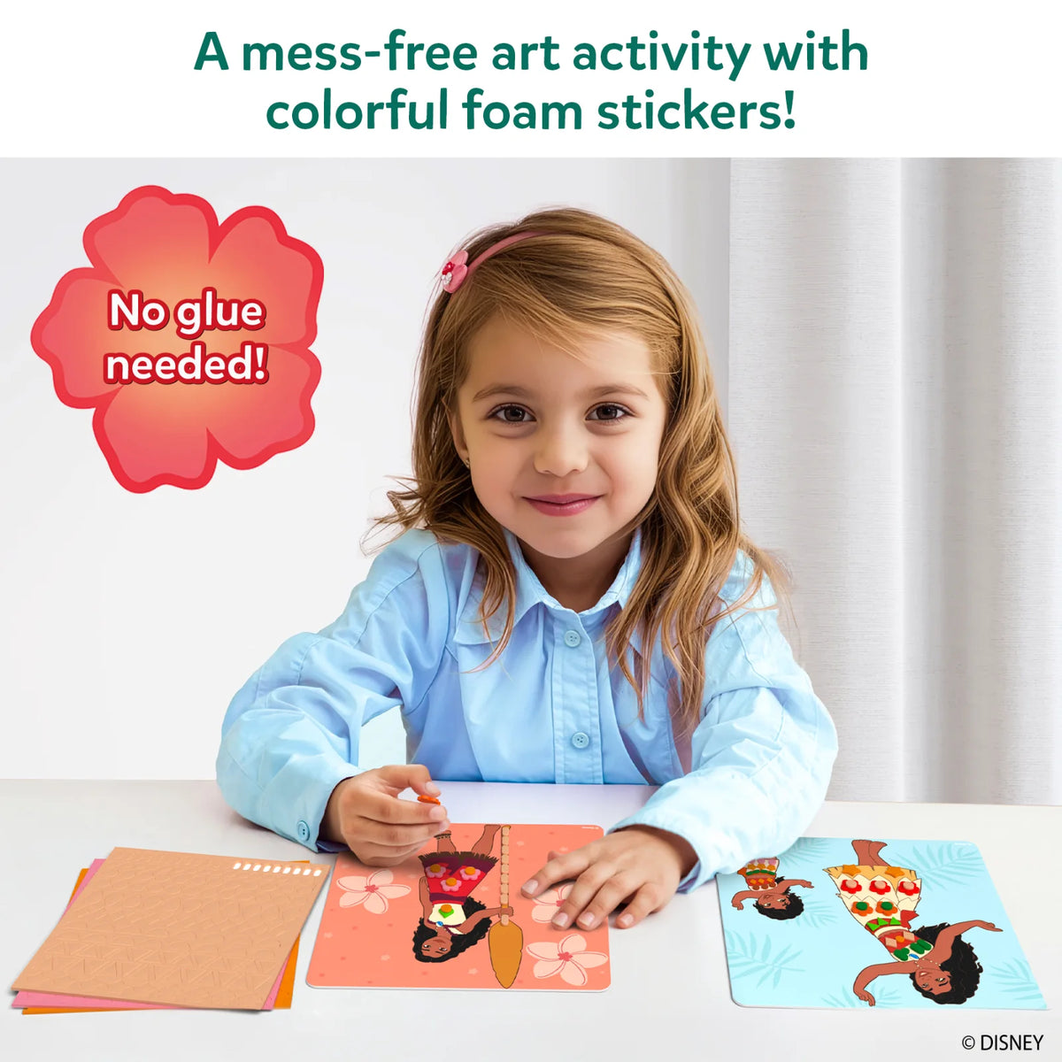Smiling girl in a light blue shirt pressing foam stickers onto a coral Moana picture board at a white table, beside a blue board of Moana and young Moana and a stack of foam sticker sheets. Text: A mess-free art activity with colorful foam stickers, with a red flower badge reading No glue needed.