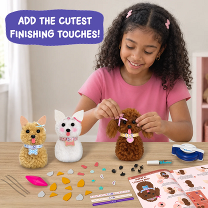 A smiling child in a pink T-shirt adds a pink bow to a brown yarn pom-pom puppy. Two finished puppies in tan and white stand beside it, with collars, charms, a pom-pom maker, marker, decorative pieces, yarn accessories and illustrated instructions arranged on a wooden table.