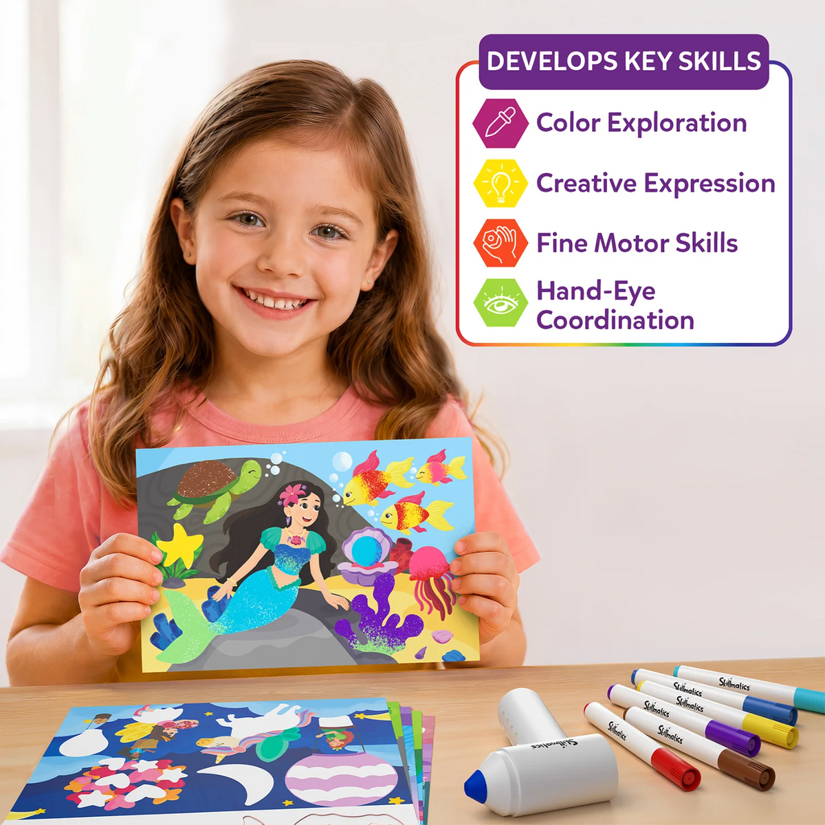 A smiling girl holds a colorful mermaid scene featuring a turtle, bright fish, coral and glittery sea details. Beside her, a panel titled “Develops Key Skills” lists color exploration, creative expression, fine motor skills and hand-eye coordination; activity boards and markers sit on the table.