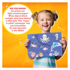 Smiling girl holding a cyanotype sun print from Magical Sun Art Animals Kit